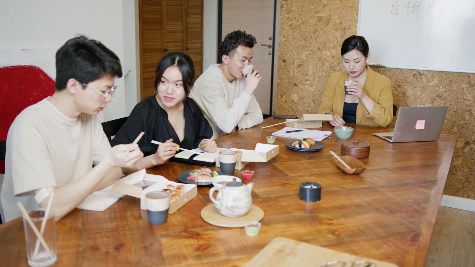 Colleagues sharing lunch around a wooden table in an office Colleagues sharing lunch around a wooden table in an office