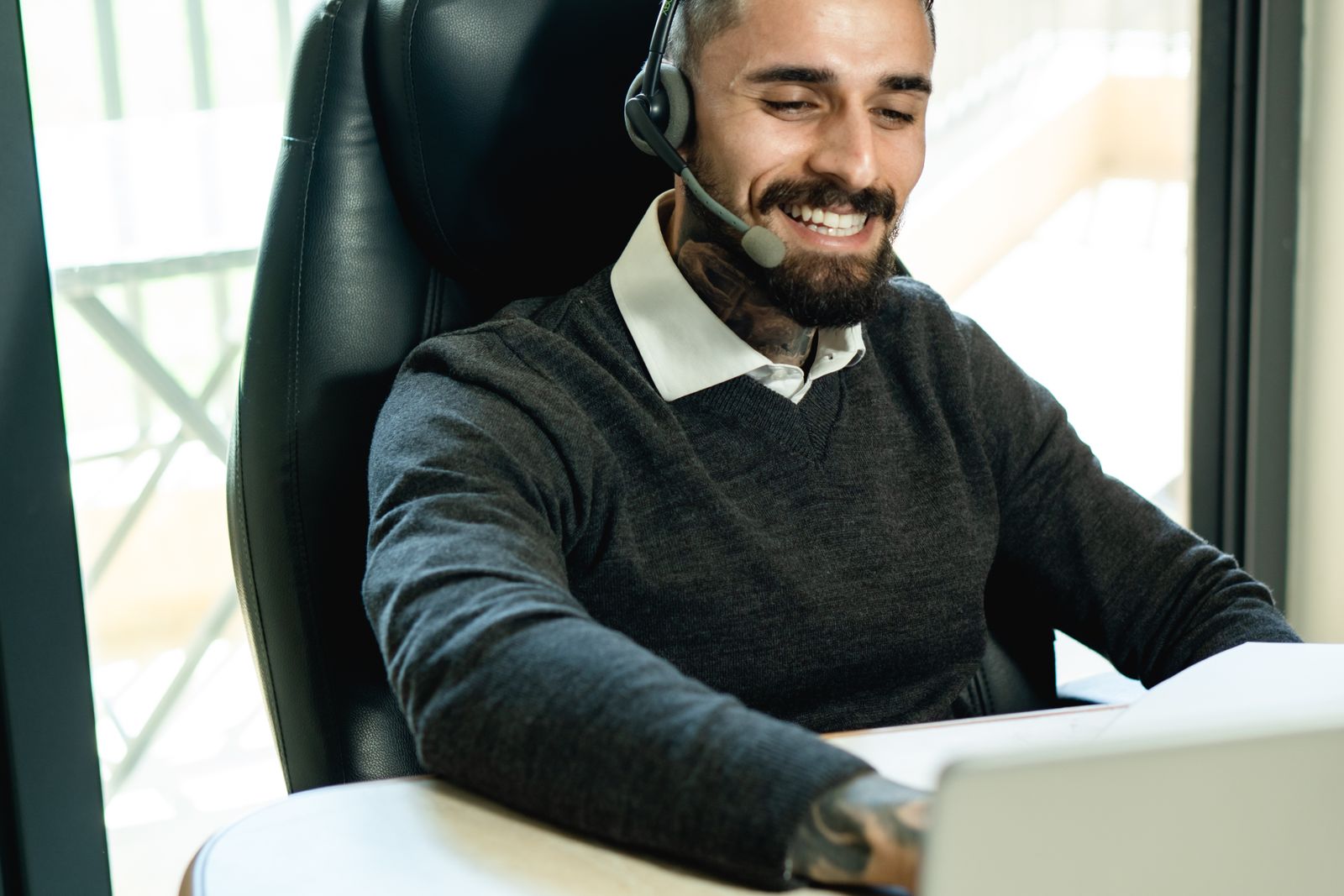A smiling support person wearing a headset at a laptop A smiling support person wearing a headset at a laptop